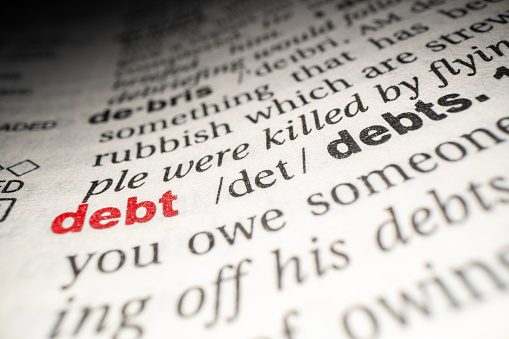 Closeup of English dictionary page with word Debt.