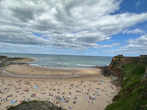 Photo of people on the beach of a seaside cove in Tynemouth, UK