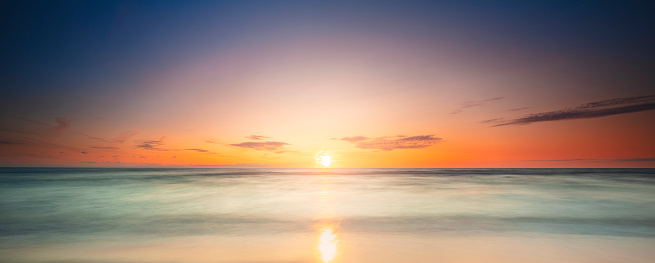 Calm sea with sunset sky and sun through the clouds over. Meditation ocean and sky background. Tranquil seascape. Horizon over the water.