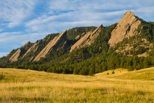 The early morning light hitting the Boulder Colorado flatirons. The Flatirons are rock formations in Boulder, Colorado consisting of flatirons. There are five large, numbered Flatirons ranging from north to south (First through Fifth, respectively) along the east slope of Green Mountain, and the term 