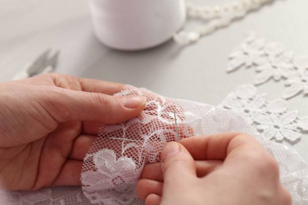 istock Dressmaker working with beautiful white lace at table in atelier, closeup 1499588933