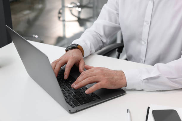 istock Man working on laptop at white desk in office, closeup 1499592488