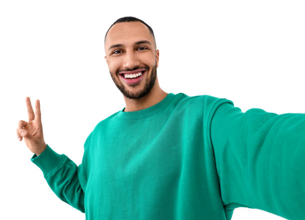 istock Smiling young man taking selfie and showing peace sign on white background 1499592622