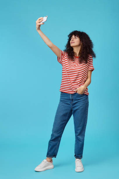 istock Beautiful young woman taking selfie on light blue background 1499592652