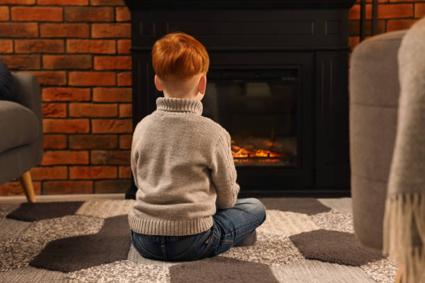 istock Boy siting on floor near fireplace at home, back view 1499593235
