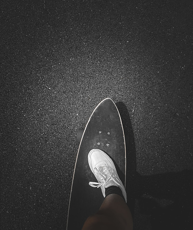 Riding a longboard down a street at night