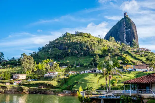 A photo of Guatape with the rock of Guatape seen in the top right of the photo. The rock stands 656 feet high and there are 708 steps leading to the top.