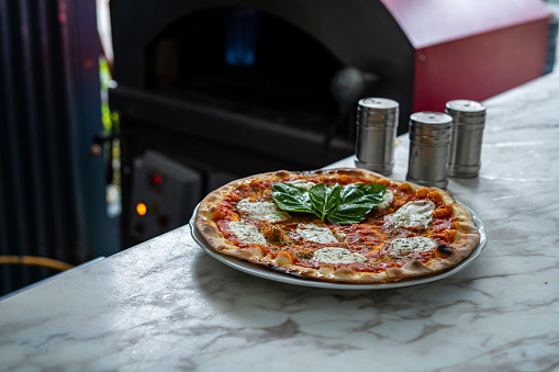 Chef of Latin ethnicity between the ages of 30-40 is making a pizza in a kitchen