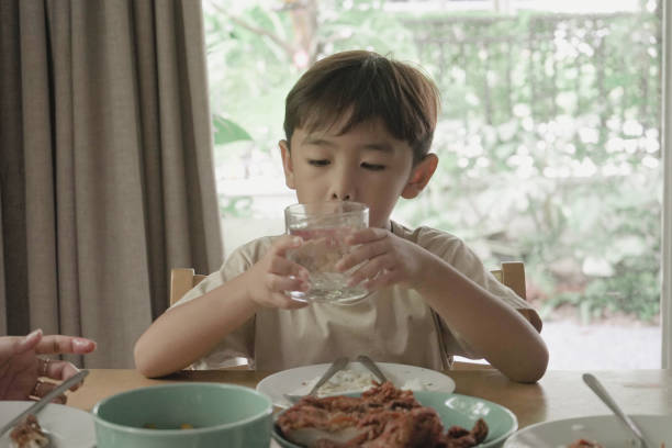 istock Child Boy drinking water from a glass on the table 1499625585