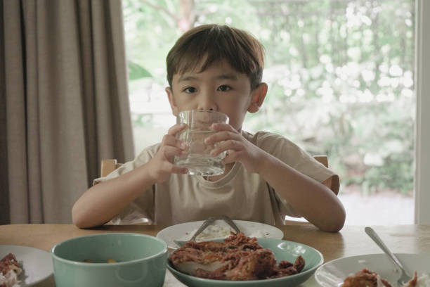 istock Child Boy drinking water from a glass on the table 1499625589