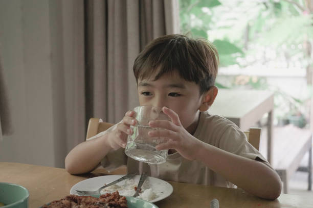 istock Child Boy drinking water from a glass on the table 1499625604