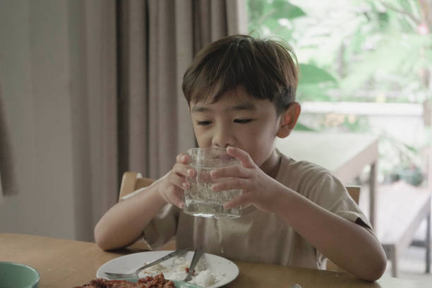 istock Child Boy drinking water from a glass on the table 1499625606
