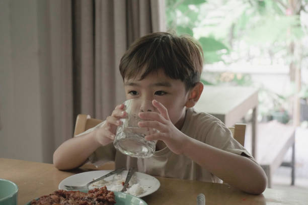 istock Child Boy drinking water from a glass on the table 1499625608