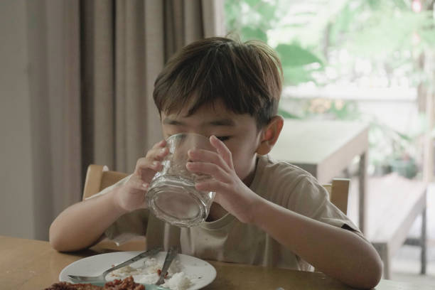 istock Child Boy drinking water from a glass on the table 1499625618