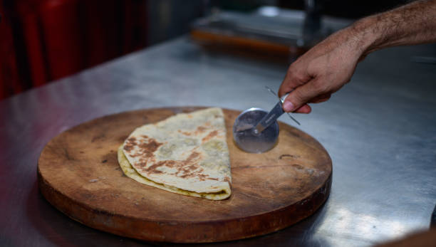 istock Cutting a folded Tortilla with a roti cutter by the chef in a restaurant. 1499636573