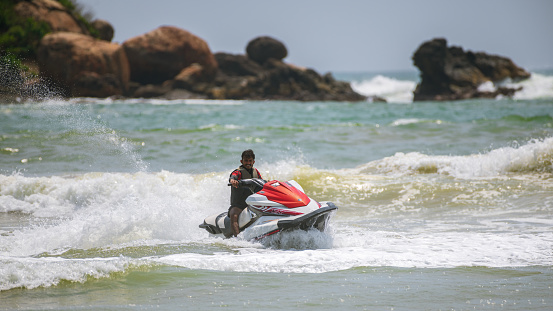 Weligama, Sri Lanka - 10 29 2022: Young male Jet sky rider enjoying the summer vacation on a tropical ocean beach.
