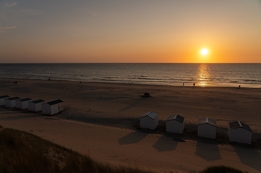 By the sea there is a row of beach huts side by side ,whit the sun go down