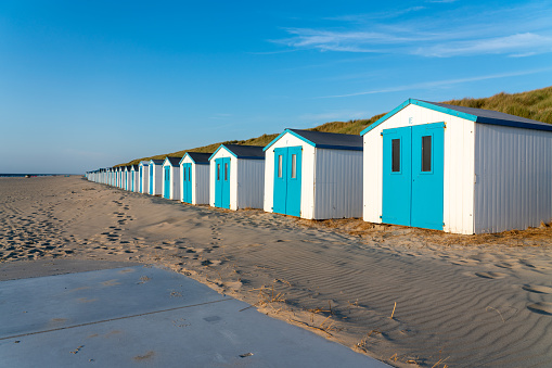 By the sea there is a row of beach huts side by side