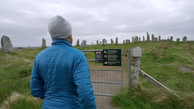 Woman visits calanais standing stones on cloudy day