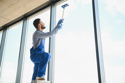 Young man cleaning window in office.