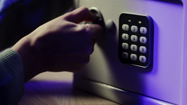 Close up shot of hand opening small safe with number code in dark room