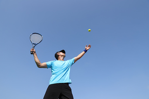 A asian tennis player serving on a tennis court.