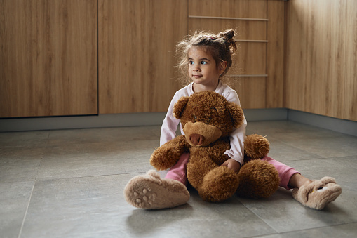 Small girl with chickenpox hugging teddy bear.