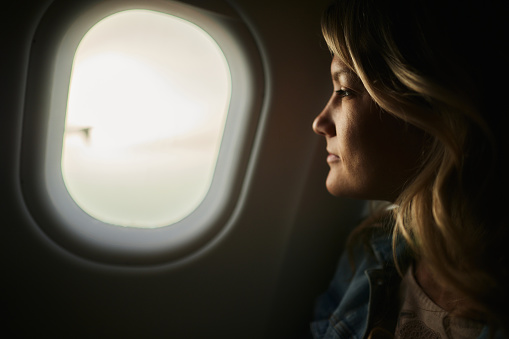 Profile view of young woman day dreaming while going on a trip by plane.