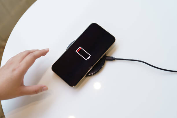 istock Charging mobile phone battery with wireless charging device in the table. Smartphone charging on a charging pad. Mobile phone near wireless charger Modern lifestyle technology concept. 1499659668