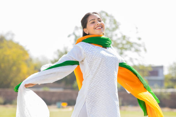 portrait of happy young indian woman wearing traditional white kurta and tricolor duppata running at park. celebrating independence day or republic day. - kurta imagens e fotografias de stock