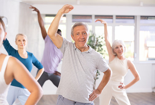 Energetic elderly man attending group choreography class, learning modern dynamic dances. Concept of active lifestyle of older generation