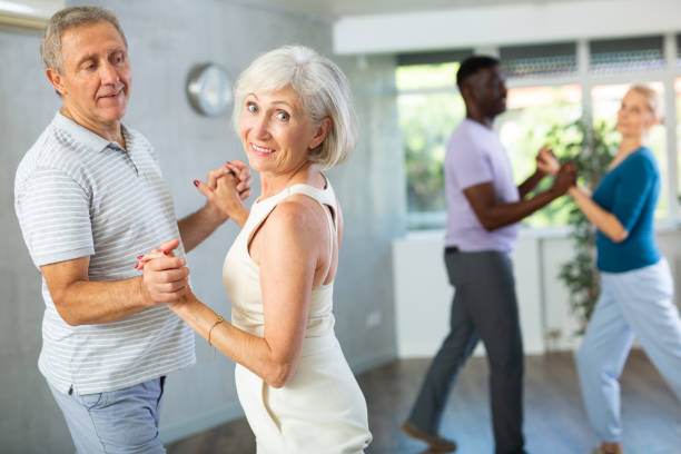 Mature men and women practicing Ballroom dances in training room