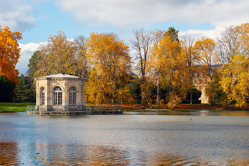 Fontainebleau, France - 2020 26 October: Pavilion in the middle of the Carp Pond with the royal castle of Fontainebleau in the background. Shot in autumn on a cloudy day.