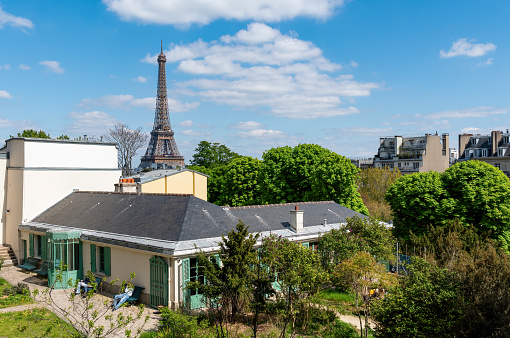 Paris, France - April 19 2023 : Exterior view of the House of Balzac (1799-1850) Museum with the Eiffel tower in the background- Paris, France. It is located in the 16th arrondissement.