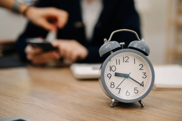 istock Alarm clock on the desk. Business working in modern office building or home at night using laptop. 1499669677