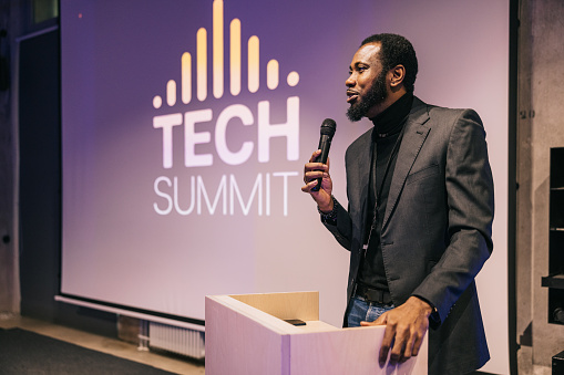 Business people take center stage, addressing an attentive audience at a tech conference. With a commanding presence, they share their insights, weaving a narrative that resonates with the crowd.