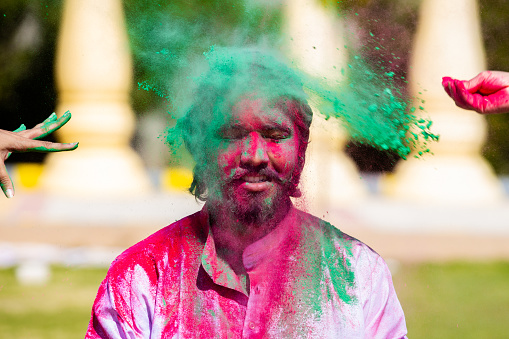 Portrait of Indian man celebrating Holi festival with colorful powder or gulal. Closeup.