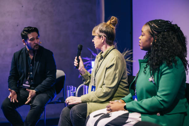 Diverse business people talking during panel discussion at tech conference. stock photo