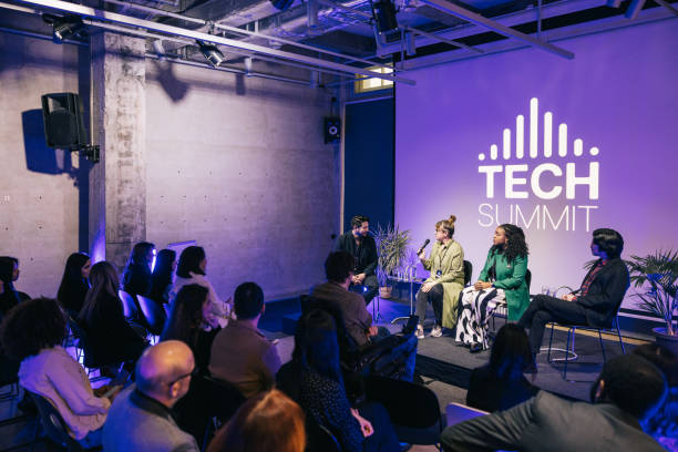 Diverse audience listening closely to lively panel discussion at tech conference. stock photo