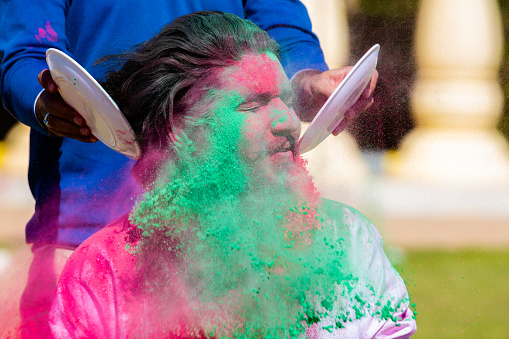 Portrait of Indian man celebrating Holi festival with colorful powder or gulal. Closeup.