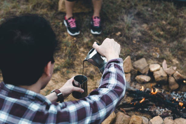 Camping coffee break outdoor and pours coffee, Making coffee bean grinder manual process on the campfire, Tourism Camping Trip, Outdoor Adventure of camper.