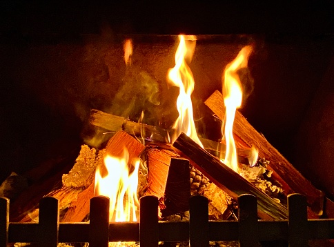 Horizontal close up still life of open fire place flames burning timber pine cones and twigs in winter home Australia