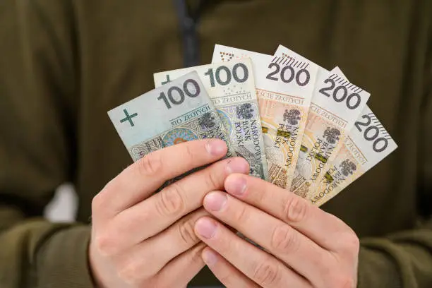 Polish cash banknotes PLN 800 held in male hands in the form of a fan, closeup,  800+