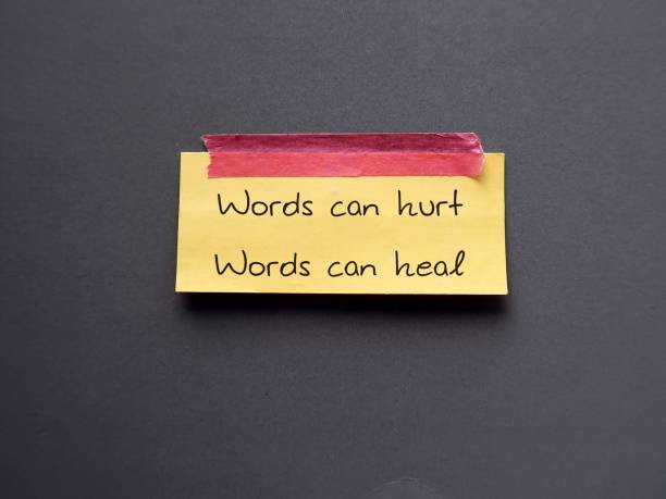istock Yellow note stick on blue background with text Words can hurt Words can heal - to remind language have power to harm or heal - word choice matters most so choose wisely 1499674903