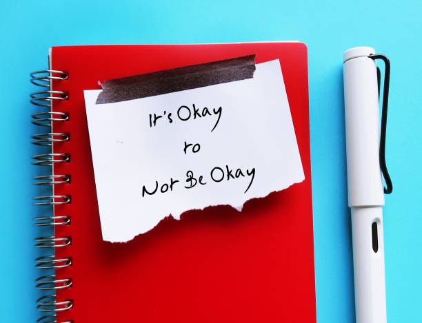 istock Torn note paper stick on red notebook with text written IT'S OKAY TO NOT BE OKAY, means feelings and emotions expressing are valid no matter what they are, it is normal to say you are not okay 1499676180