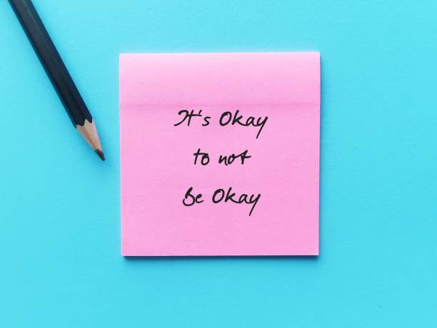 istock Pink note paper stick on red copy space background with text written IT'S OKAY TO NOT BE OKAY, means feelings and emotions expressing are valid no matter what, it is normal to say you are not ok 1499676654