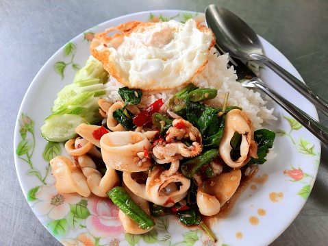 Eating Stir fried Spicy Squid Basil and Fried Egg on Rice - Thai Street Food.