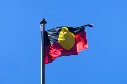 The Australian Aboriginal flag flies in the wind on the Queen Victoria Building in the central business district of Sydney.  This image was taken on a sunny winter morning on 19 June 2023.