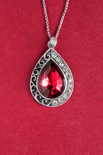 Vintage silver ruby pendant on red background closeup