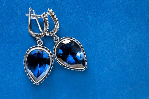 Vintage silver sapphire earrings on blue color background closeup